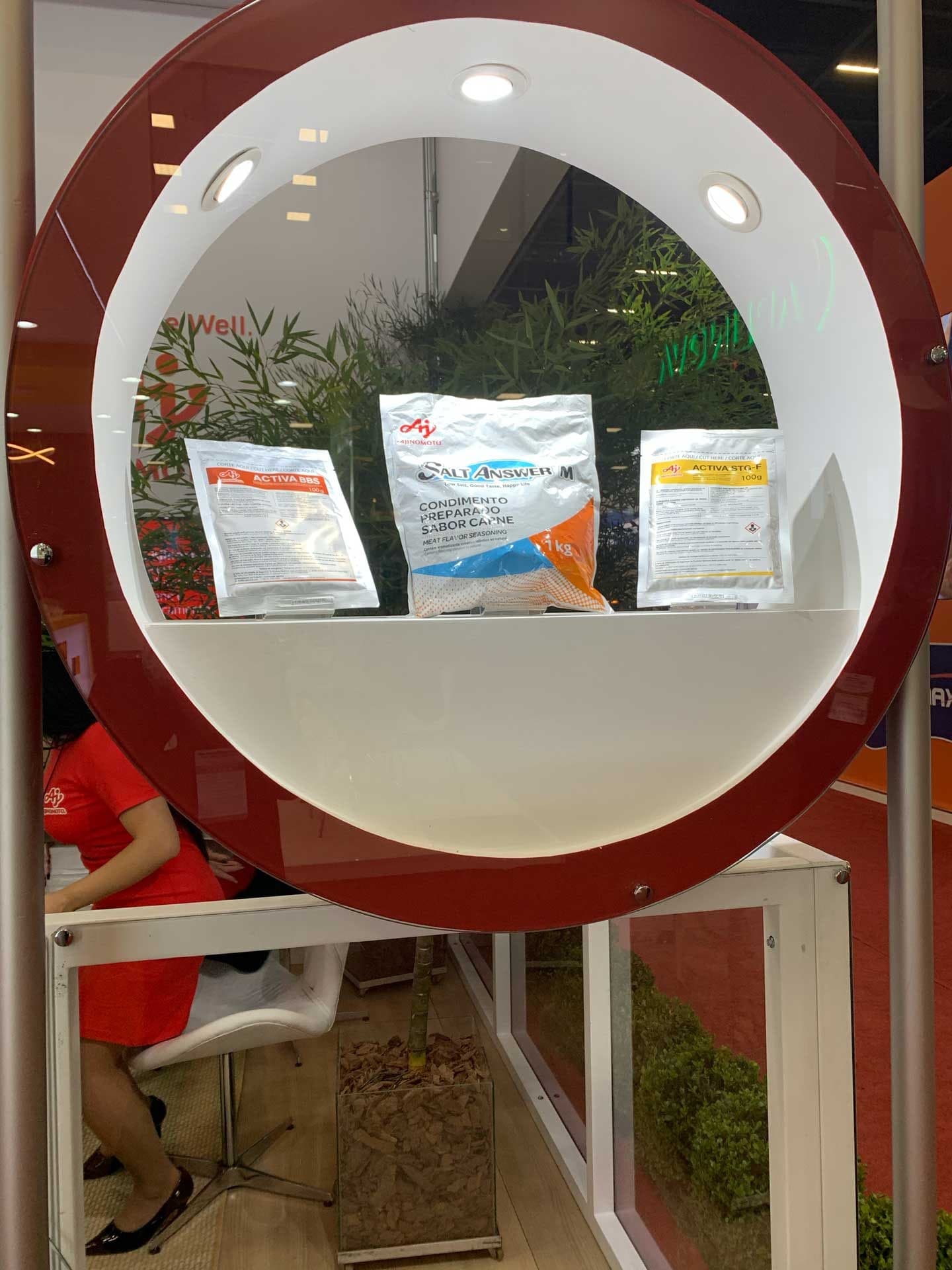 Detalhe de uma das vitrines circulares do estande: sacos de Activa BBS, Salt Answer e Activa STG-F expostos sobre a prateleira branca, com rotulagem bilíngue em português e inglês.