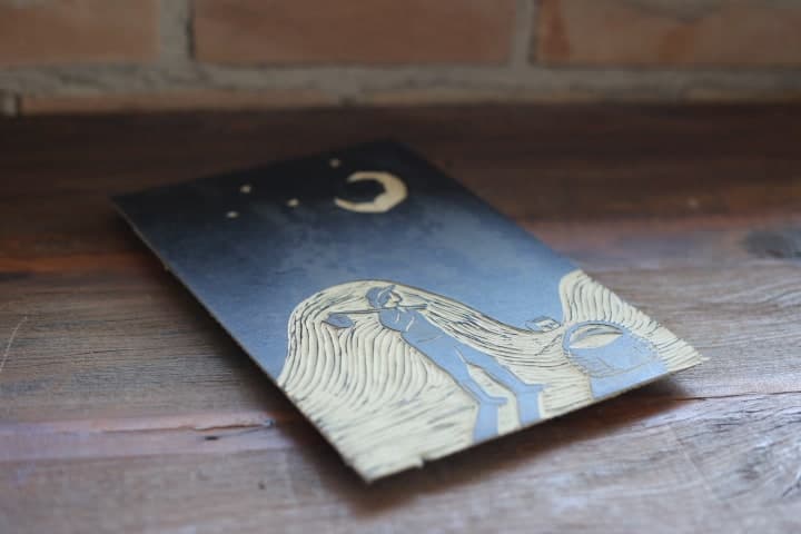 Matriz de xilogravura da cena noturna, com lua crescente e estrelas entalhadas em fundo escuro.