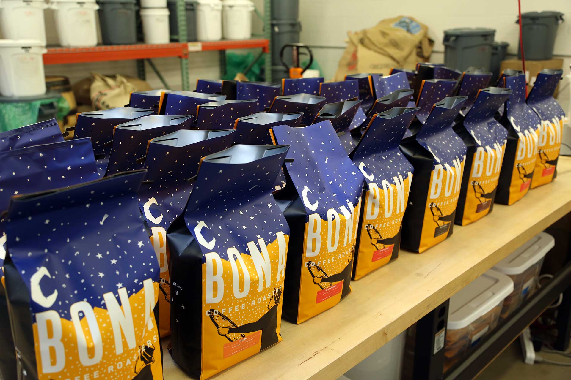Sacolas da Bona com a marca aplicada, mostrando a extensão do sistema para além da embalagem de café.