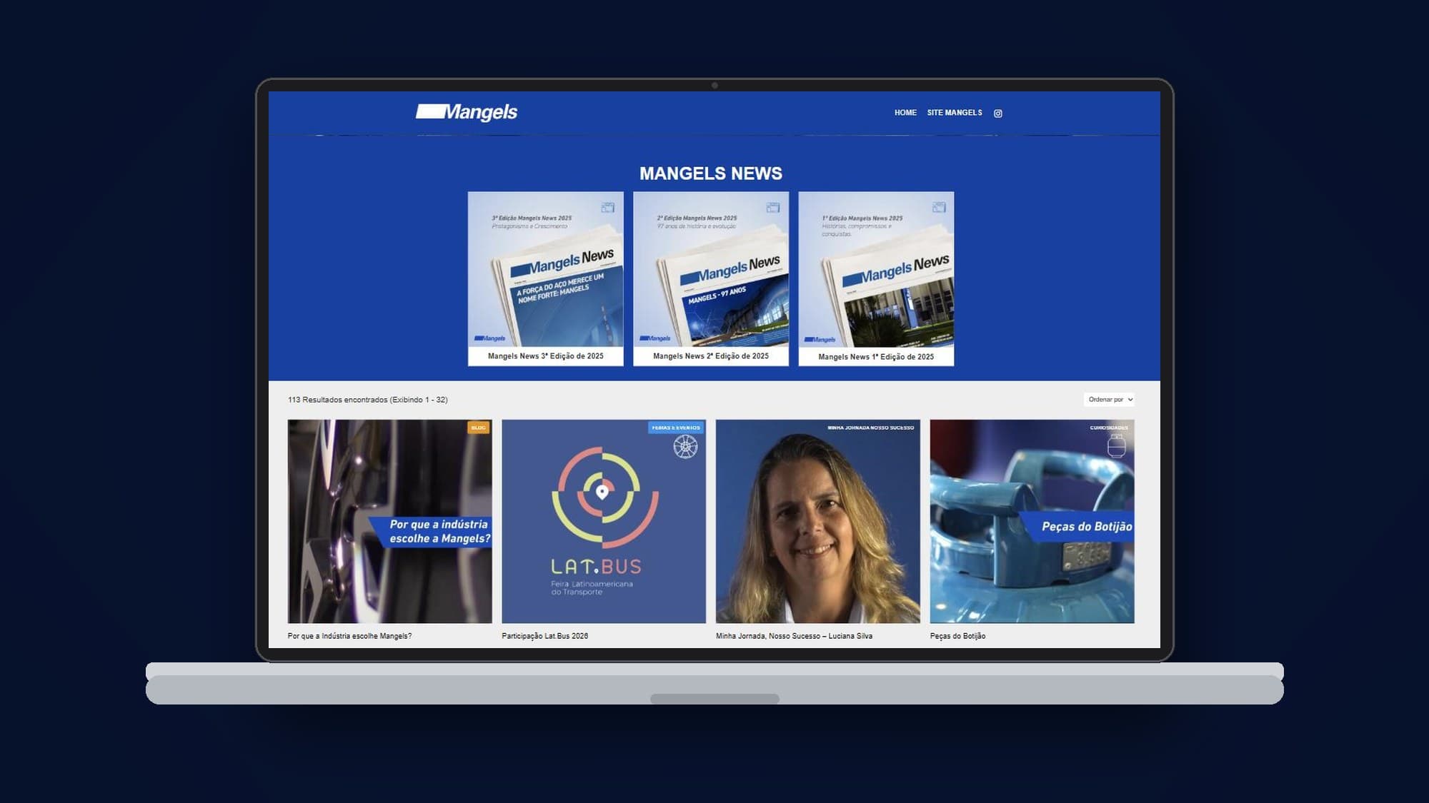 Hub de notícias da Mangels num notebook: grade de artigos com etiquetas de categoria como Minha Jornada Nosso Sucesso, Blog e Feiras e Eventos, sobre o azul da marca.